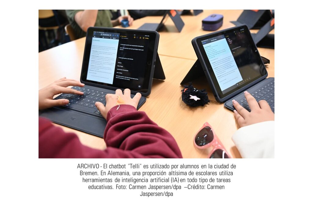 Vista desde arriba de una mesa escolar grande donde varios niños y niñas interactúan con pantallas de tabletas con teclado y escriben en ellas.